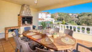 una mesa de madera y sillas en un balcón con chimenea en Costacabana - Villa Holiday, en Lloret de Mar