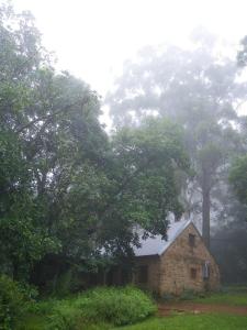 an old stone house in a field with trees at KLIPINNIBOS Nature Farm in Schoemanskloof