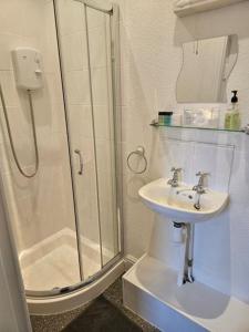 a white bathroom with a shower and a sink at Hermosa Guest House in Scarborough