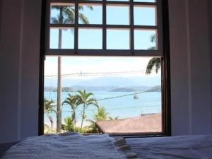um quarto com uma janela com vista para o oceano em Pousada Sunshine Beach em Angra dos Reis