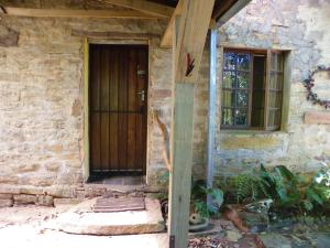 a stone house with a wooden door and a window at KLIPINNIBOS Nature Farm in Schoemanskloof