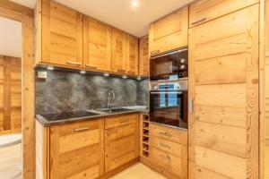 - une cuisine avec des placards en bois et un évier dans l'établissement Beautiful wooden chalet in La Plagne, à Aime La Plagne