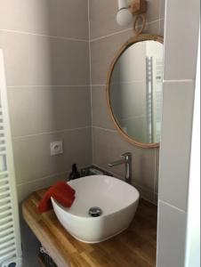 ein Badezimmer mit einem weißen Waschbecken und einem Spiegel in der Unterkunft Gîte Cala Verde Jardin, à 4km de la première plage in Audenge