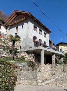 un edificio con balcón en la parte superior de una pared de piedra en Tolles Loft in den Tessiner Bergen en Corcapolo