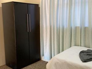 ein Schlafzimmer mit einem schwarzen Schrank neben einem Bett in der Unterkunft Tanzanite Guesthouse in Dannhauser