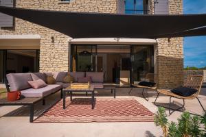 een patio met een bank en een tafel en stoelen bij Stone charming villa pool and garden in Gordes in Gordes