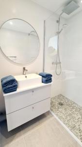 a white bathroom with a sink and a mirror at MAGNIFIQUE APPARTEMENT T4 GRAND STANDING - VUE MER PANORAMIQUE ET PISCINE in Bandol