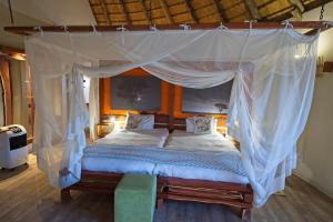 a bedroom with a canopy bed with white sheets and pillows at Onjala in Eorondemba