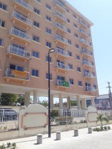 a large pink building with white balconies and a street light at apartamento som do mar in Fortaleza