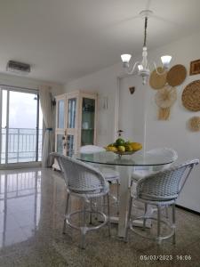 a dining room with a glass table and chairs at apartamento som do mar. in Fortaleza