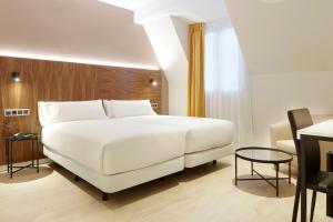 a bedroom with a large white bed and a table at Hotel Arrizul Congress in San Sebastián