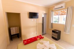 um quarto com uma cama e uma televisão na parede em Pousada Três Praias em Guarapari