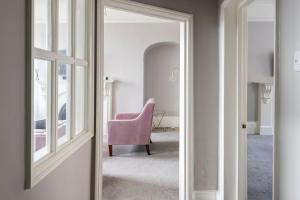 a mirror in a room with a pink chair at Bladud Buildings in Bath