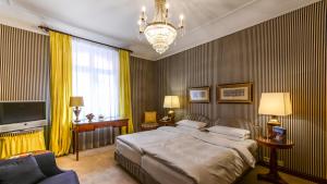 um quarto com uma cama, uma televisão e um lustre em Hotel Opera em Munique