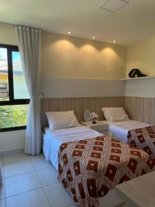 una camera d'albergo con due letti e una finestra di Bangalô frente ao mar Vg Sun Cumbuco a Caucaia Altre 5 foto