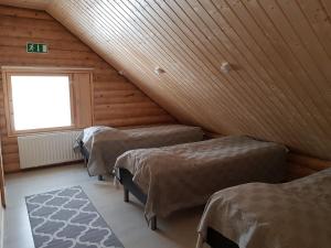 VuontisjärviにあるTunturihuvila IIIのベッド3台と窓が備わる屋根裏部屋