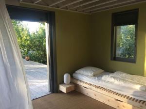 een slaapkamer met een bed en een groot raam bij MAISON CALME ET LUMINEUSE OUVERTE SUR LA NATURE in Truinas