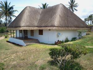 a small white house with a thatched roof at Blue Moon Beach Holiday Resort in Inhambane