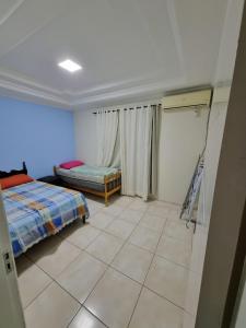 um quarto com uma cama e piso em azulejo em Casa a 500 metros da praia em balneário piçarras em Piçarras