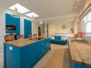 a large kitchen with blue cabinets and a living room at Marine House in Gullane