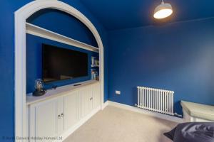a blue room with a large flat screen tv at Marine House in Gullane