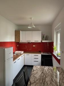 una cucina con pareti rosse, armadi bianchi e tavolo di Apartment M & M a Spalato (Split)