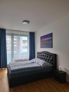 1 dormitorio con 1 cama con cortinas azules y ventana en Vltava apartments, en Praga