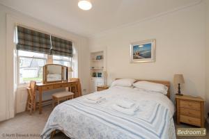 a bedroom with a bed and a desk and a mirror at Hopetoun Cottage in Gullane