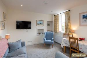 a living room with a tv and a chair and a table at Hopetoun Cottage in Gullane