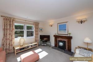 a living room with a fireplace and a television at Hideaway Cottage in Dirleton