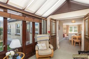 a room with a conservatory with a chair and a table at Hideaway Cottage in Dirleton