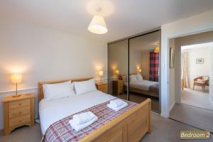 a bedroom with a large bed and a mirror at Hideaway Cottage in Dirleton