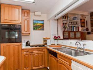 a kitchen with wooden cabinets and a sink at Greylag Cottage in Gullane