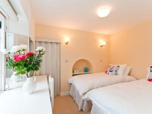 a bedroom with two beds and a vase of flowers on a table at Greylag Cottage in Gullane