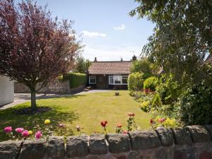 a garden with a stone wall and flowers at Greylag Cottage in Gullane