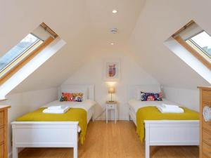 2 Betten in einem Dachzimmer mit 2 Fenstern in der Unterkunft Curlew in North Berwick