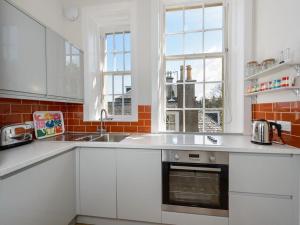 a kitchen with white cabinets and a sink and windows at Havana in North Berwick