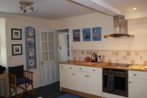 a kitchen with white cabinets and a stove top oven at Harbourside Cottage in North Berwick +6 photos