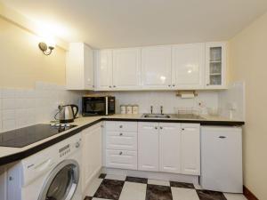 uma cozinha com armários brancos e uma máquina de lavar roupa em Harmony Undercroft em North Berwick