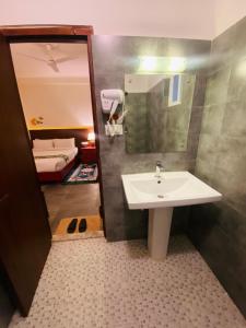 a bathroom with a sink and a mirror and a bed at Three Jewels Boutique Hotel in Pokhara