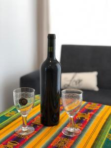 a bottle of wine and two glasses on a table at Tampu, the Container House in Cafayate