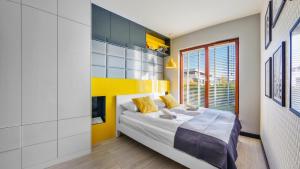 1 dormitorio con cama y pared de acento amarillo en Apartamenty Sun & Snow Gdynia Nowe Orłowo en Gdynia