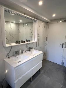 La salle de bains est pourvue de 2 lavabos et d'un grand miroir. dans l'établissement Un moment de détente Maison avec balnéothérapie ., à Prades