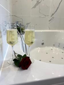 two glasses of wine and a rose on a counter at Un moment de détente Maison avec balnéothérapie . in Prades