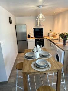 a kitchen with a wooden table with plates on it at Un moment de détente Maison avec balnéothérapie . in Prades