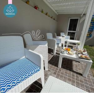 a patio with white wicker chairs and a table with food on it at Hostería Magnolia in Villa Gesell