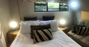 a bedroom with a white bed with two lamps at Gecko Cottages in Hectorspruit