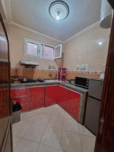 a kitchen with red cabinets and a white refrigerator at شقق مفروشة الفري in Laayoune