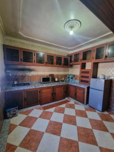 a kitchen with wooden cabinets and a checkered floor at شقق مفروشة الفري in Laayoune