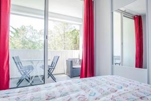 - une chambre avec un lit et un balcon avec des rideaux rouges dans l'établissement Bleu soleil * Clim * Parking privé * Chambre * Terrasse, à La Grande Motte